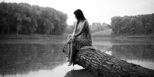 woman sitting alone on log