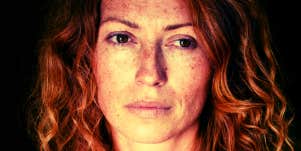 redheaded woman with freckles staring into space with sad eyes