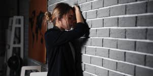 woman upset leaning on wall