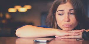 woman waiting next to her phone for a guy who is ignoring her texts