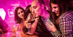 man surrounded by women in a bar