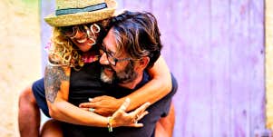 middle age couple laughing, woman riding on her husband's back