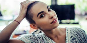 woman with very short hair looks peacefully at the camera