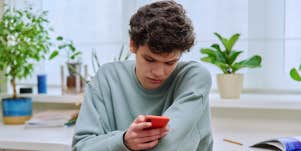teen guy texting in bedroom