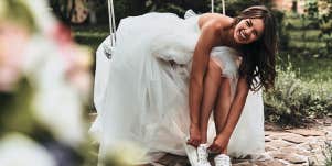 girl in wedding dress putting on tennis shoes