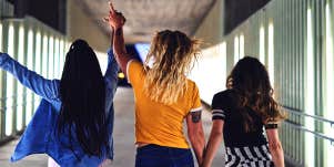 group of three teenaged girls walking down hallway together
