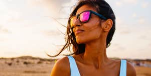 South Asian woman looks sideways in the desert, wearing sunglasses