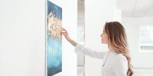 woman looking at painting hanging on the wall