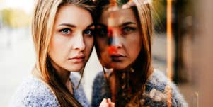 serious woman leans against a mirror