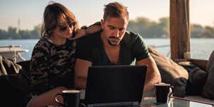 man and woman working on laptop while on vacation