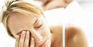tired woman rubbing eyes in bed