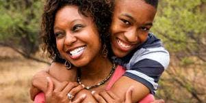 man hugging woman from behind and both are smiling