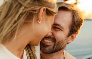 White couple hugging and smiling during picnic with their friends outdoors