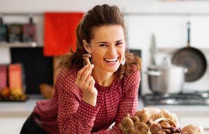 Happy young housewife with basket with mushrooms in kitchen