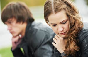 woman sitting on bench with man looking away contemplating sadly