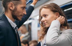 couple standing in a subway daring each other with their eyes