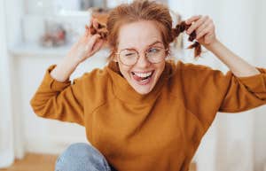 Cute mischievous young redhead woman pulling her pigtails while winking and sticking out her tongue with a teasing expression