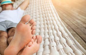 Man in hat in a hammock on a summer day bare toes