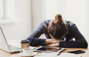Overwhelmed woman with head on desk