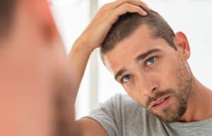 man with his hands on his head looking in a mirror