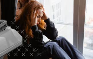 depressed woman sitting by window
