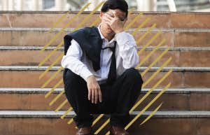 unemployed man, sitting on tsteps outside with his hands rubbing his eyes