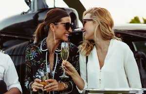 Women with champagne walking off a private helicopter