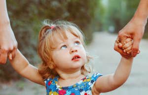 little girl holding parents hands