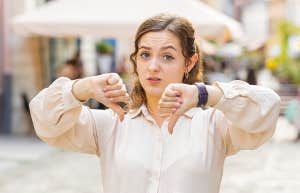 woman standing in street giving thumbs down