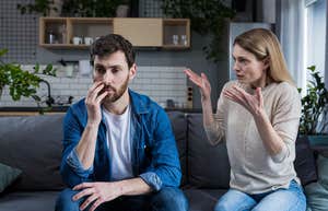 man and woman sitting on sofa at home arguing