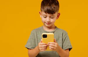 little boy on phone in front of orange background