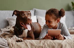 Pitbull laying with toddler on bed. 