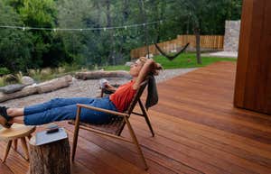 woman relaxes in lawn chair on back porch