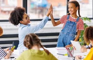 Students giving a high five to her teacher for winning a pool party.