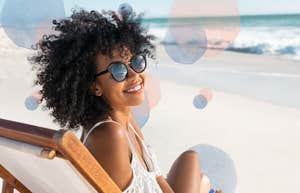 Happy Black woman with natural curly hair living her dream life on a beach