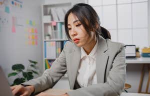  overworked and tired businesswoman sitting at desk with laptop