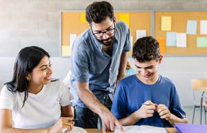teacher helping high school students with their class work