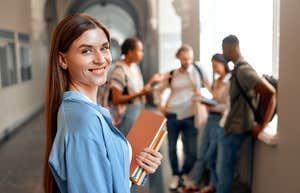 college student standing by herself near a group of students
