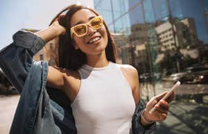 woman outside holding phone with yellow sunglasses