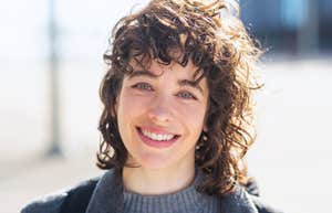 Subtle Signs You're An Intelligent And Self-Aware Outcast smiling intelligent woman standing outside