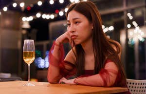 sad woman sitting alone at bar with glass of wine