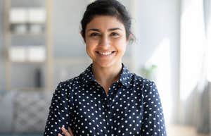 Millennial woman smiling with her arms crossed at work. 