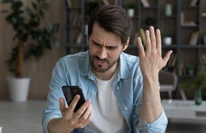 man looking at his phone angry and frowning
