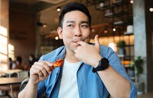 man eating chicken wings with his hands