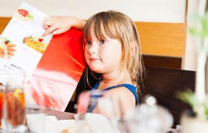 little girl pointing at what she wants on a restaurant menu