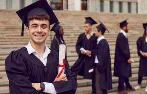 group of graduates standing outside school with one looking at camera