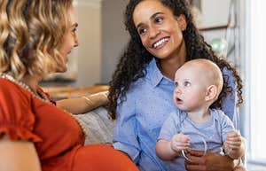 Mixed race woman with expecting mother talking and playing with baby