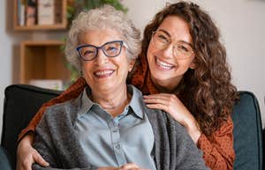 Young woman smiling and hugging her older mother on the couch
