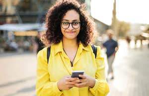 Woman smiling while making money on app on phone. 