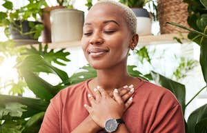 Woman smiling with her eyes closed holding her hands to her chest.